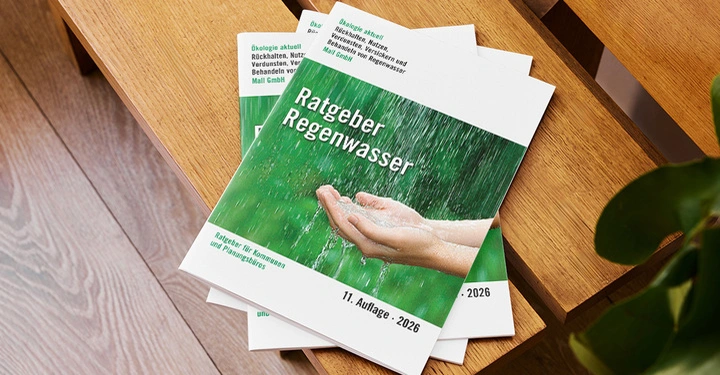 Mehrere Broschüren mit Titel Ratgeber Regenwasser liegen auf moderner Holzbank.