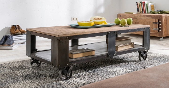 Holztisch steht auf Teppich im Wohnzimmer Bücher und Früchte darauf Regal mit Büchern im Hintergrund Schuhe links daneben heller Boden und weiße Wände umgeben die Szene