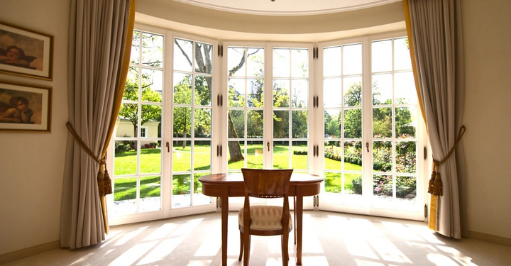 Galerie-Bild 6: Tisch und Stuhl stehen vor großen Fenstern Aktionen sind keine Menschen sind im Raum sichtbar Die Fenster bieten den Blick auf einen sonnigen grünen Garten mit Bäumen In der Nähe hängen Bilder an der Wand