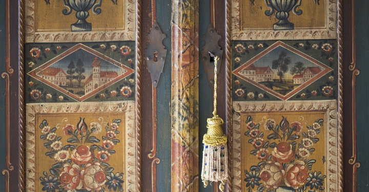 Galerie-Bild 7: Holztür bemalt zeigt Vasen mit Blumen und städtische Gebäude in Rauten Türgriff mit Quaste Dekoration im traditionellen Stil bemalter Holzrahmen Umrisse deuten auf eine historische Einrichtung hin