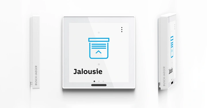 Ein quadratisches Digitaldisplay zeigt das Symbol einer Jalousie mit dem darunterstehenden Text Jalousie. Das Display ist von zwei seitlichen weißen Geräten mit der Aufschrift BUSCH-JAEGER umgeben.