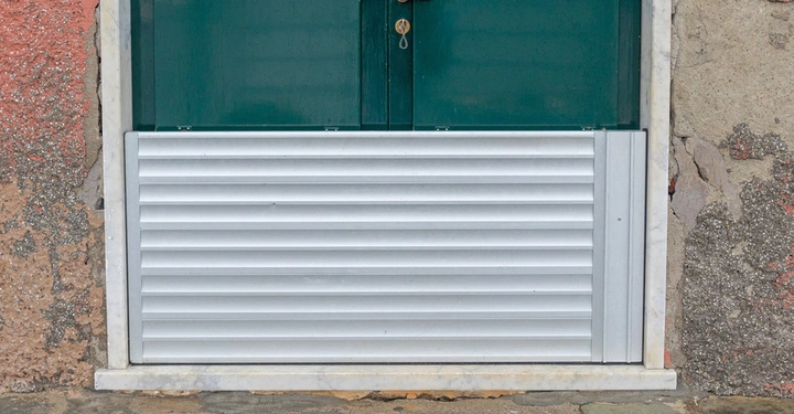 Dammbalken aus Alu schützen das untere Drittel einer tiefgrün gestrichenen Eingangstür vor Hochwasser