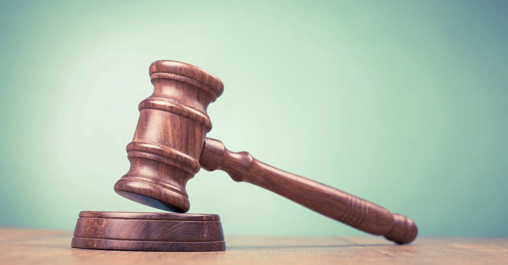 Richterhammer liegt auf Holzoberfläche vor grünem Hintergrund