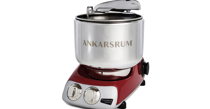 Küchenmaschine mit silberner Schüssel und rotem Sockel steht still auf einem weißen Hintergrund. Text auf der Schüssel lautet ANKARSRUM.