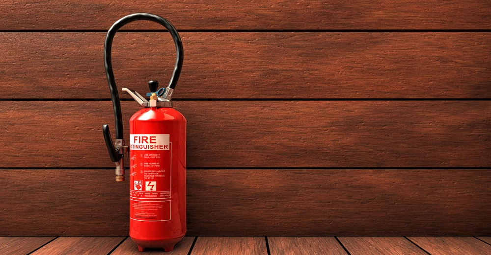 roter Handfeuerlöscher mit weißer Standardbeschriftung hängt vor vertäfelter Holzwand