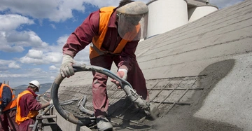 Dachdecker in Schutzkleidung installieren ein Betondach aus Ortsbeton auf einem Haus.