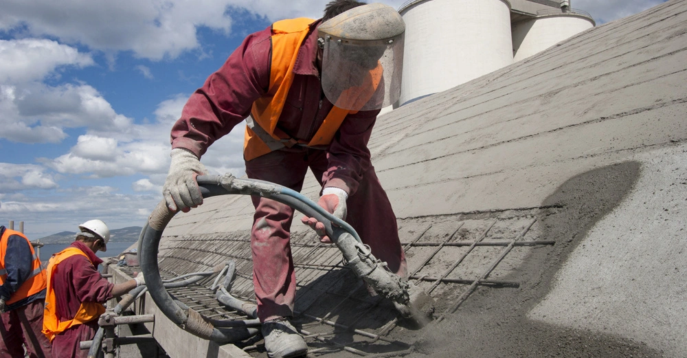 Dachdecker in Schutzkleidung installieren ein Betondach aus Ortsbeton auf einem Haus.