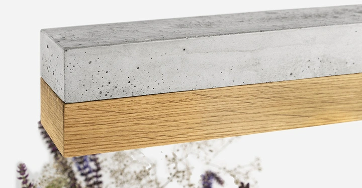 Rechteckiger Betonbalken ruht auf einem rechteckigen Holzbalken vor einem Hintergrund aus verschwommenem Laub und Blumen in verschiedenen Farben