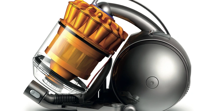 Staubsauger mit transparentem Behälter und orangefarbenen Filterkomponenten in einem modernen, grauen Gehäuse stehend auf einem weißen Hintergrund