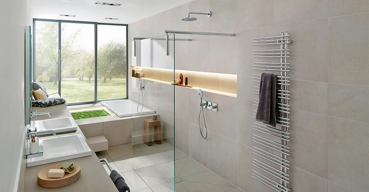 Modernes Badezimmer zwei Waschbecken links Dusche rechts große Fenster im Hintergrund neben Badewanne mit grünen Pflanzen im Inneren Handtuchhalter rechts.