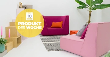 Zwei bunte Sofas stehen in einem modernen Wohnzimmer mit weißen Wänden; ein pinkes Sofa im Vordergrund und ein violettes Sofa im Hintergrund. Text: 10 PRODUKT DER WOCHE