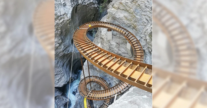 Galerie-Bild 8: Metalltreppe windet sich spiralförmig nach unten in eine schmale Felsenschlucht mit fließendem Wasser am Boden an von Felswänden umgeben.