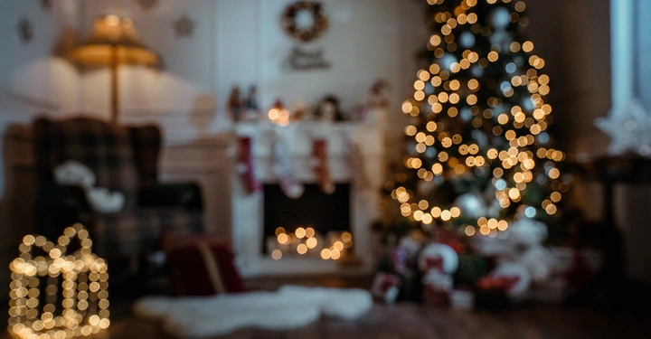 Gemütliches Wohnzimmer mit beleuchtetem Weihnachtsbaum, Kaminfeuer und leuchtender Geschenk-Deko im Bokeh-Stil.