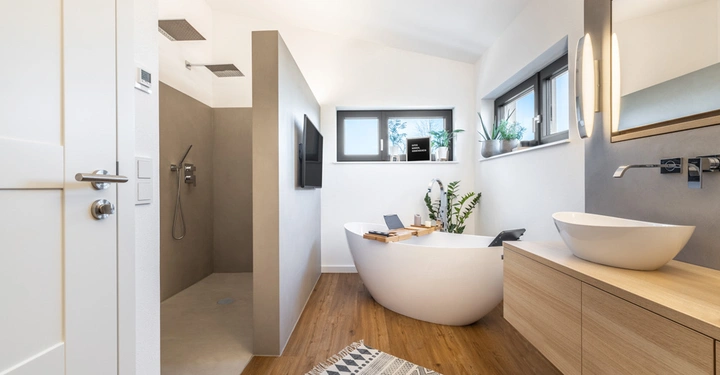 Galerie-Bild 3: Großes modernes Badezimmer mit einer freistehenden Badewanne einem Doppelwaschbecken aus Holz einer begehbaren Dusche und Pflanzen auf der Fensterbank. Text: LAMURISTA
