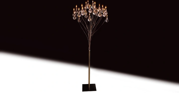 Stehlampe mit mehreren Glühbirnen hängt an Drahtarmen leuchtet in einem dunkel gehaltenen Raum auf einem weißen Boden.