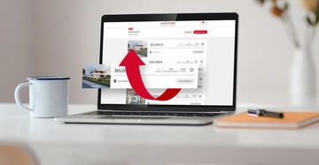 Laptop zeigt Immobilienangebote in Österreich, roter Pfeil über einem der Angebote 365.000 € 4521 Pfaffing 4 Zimmer Kauf Niedrigenergiehaus 122 m² Fläche ZUR IMMOBILIE. Links daneben eine Kaffeetasse.