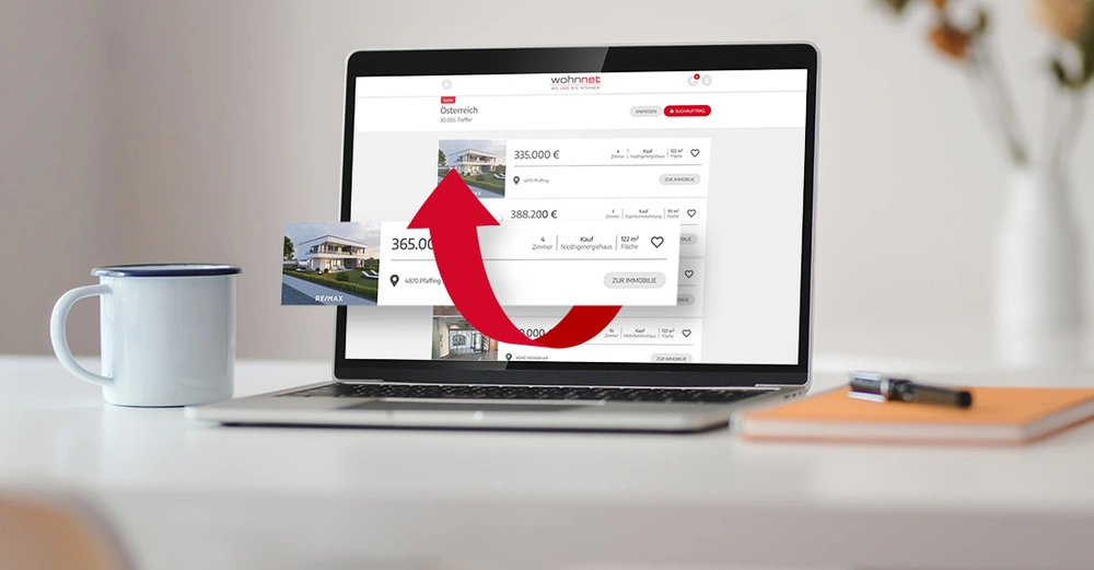 Laptop zeigt Immobilienangebote in Österreich, roter Pfeil über einem der Angebote 365.000 € 4521 Pfaffing 4 Zimmer Kauf Niedrigenergiehaus 122 m² Fläche ZUR IMMOBILIE. Links daneben eine Kaffeetasse.
