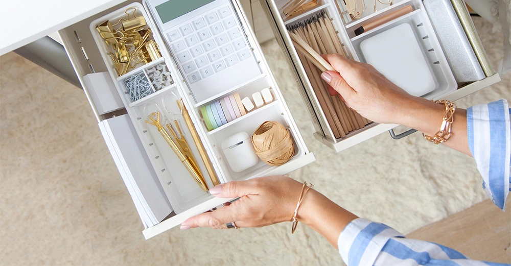 Frau mit blauem Hemd öffnet gut organisierte Schreibtischschublade.