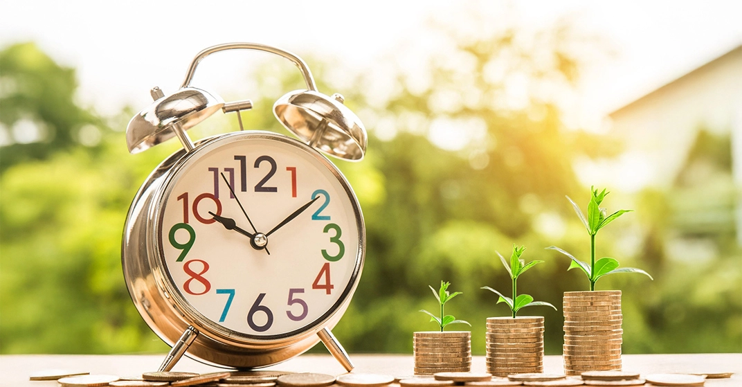 Ein Wecker auf einem Tisch mit Geldmünzen