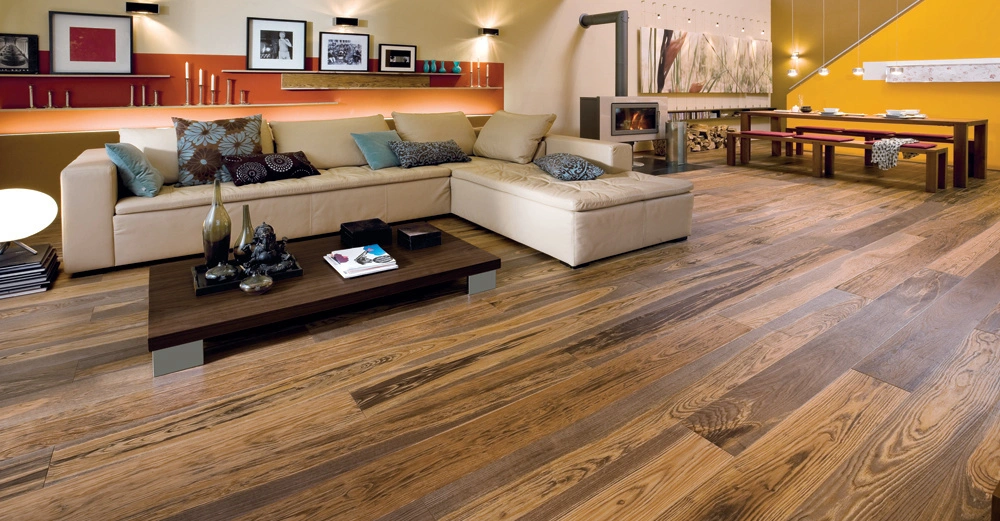 Beiges Sofa steht vor einer modernen Wand mit Regalen und Fotos in einem stilvollen Wohnzimmer mit Holzboden ein Couchtisch mit Dekorationsgegenständen und ein Esstisch befinden sich im Hintergrund neben einem Kamin.