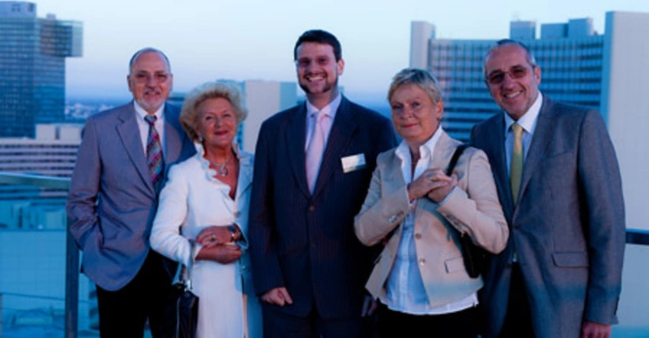 Galerie-Bild 27: Fünf Personen posieren lächelnd auf einer Dachterrasse vor einer Stadtlandschaft mit modernen Hochhäusern im Hintergrund. Die Personen sind formell gekleidet und stehen nebeneinander.