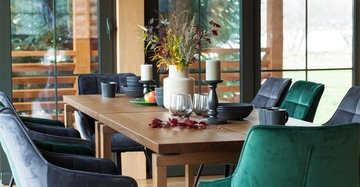 Feng Shui im Esszimmer. In diesem Raum gelungen. Gemütliche Sessel in grünem und blauem Samt stehen um einen großen Esstisch aus Holz. Große Fensterflächen, herbstliche Dekoration