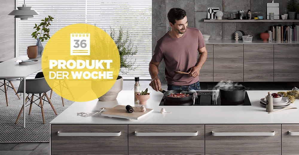 Ein Mann kocht in einer modernen Küche an einem Kochfeld. Text auf gelbem Kreis: 36 PRODUKT DER WOCHE. Im Hintergrund Esstisch mit Pflanzen und Hockern.