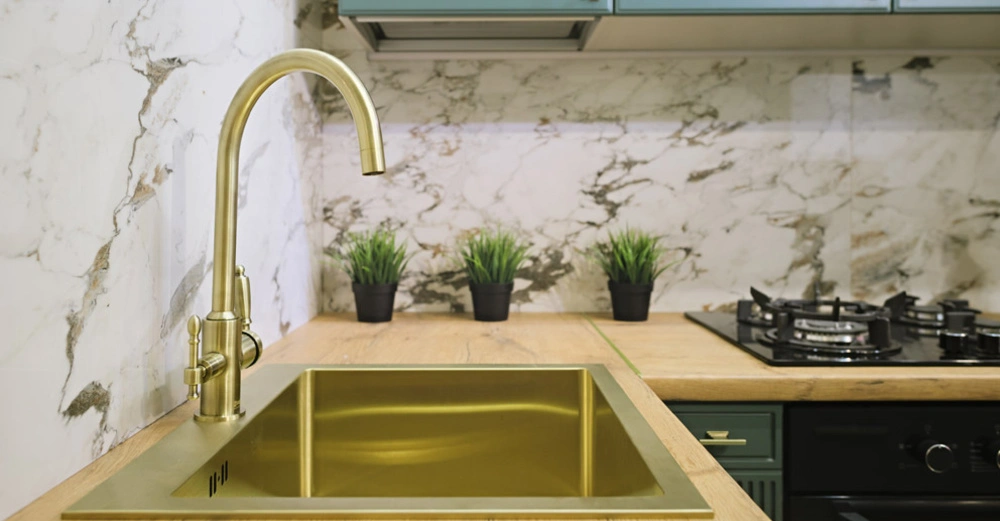 Küchenarmatur in Messing Großaufnahme einer modernen, gemütlichen Küchenzeile