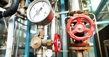 Ein Druckmessgerät zeigt den Druck an In einem industriellen Rohrleitungssystem befinden sich mehrere Ventile und Rohre in einer stark mechanisierten Umgebung