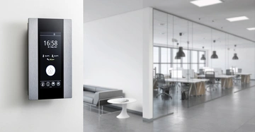 Ein Wand-Touchscreen zeigt 16 58 06 May 2021 und Raumklimadaten an Monitor links situiert In einem modernen Büro mit Glastrennwänden Bürotischen und Stühlen im Hintergrund