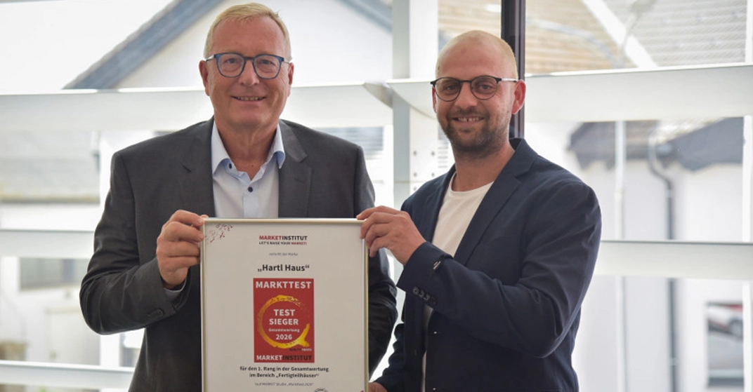 zwei Männer in Anzug und mit Brille halten stolz eine Auszeichnung in die Kamera