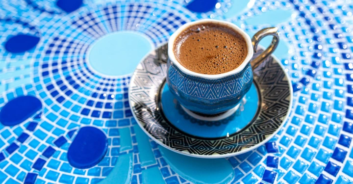 Galerie-Bild 3: Runder azurblauer Mosaiktisch, auf dem ein orientalisch gemusterte Kaffeetasse mit Untersetzer steht