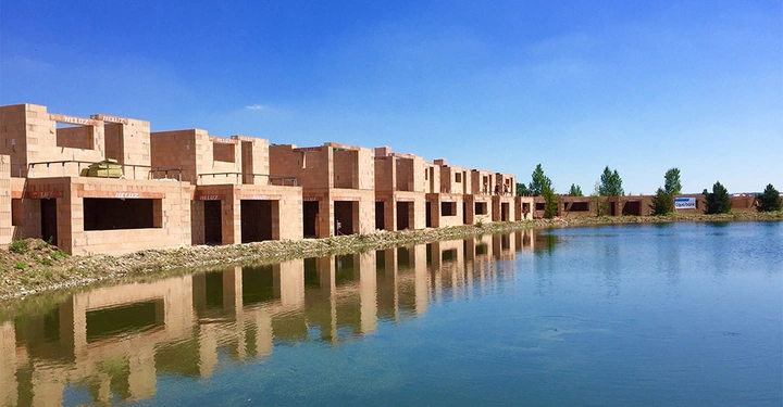 Galerie-Bild 2: Rohbau Reihenhäuser aus rotem Ziegel um blauen See herumgebaut