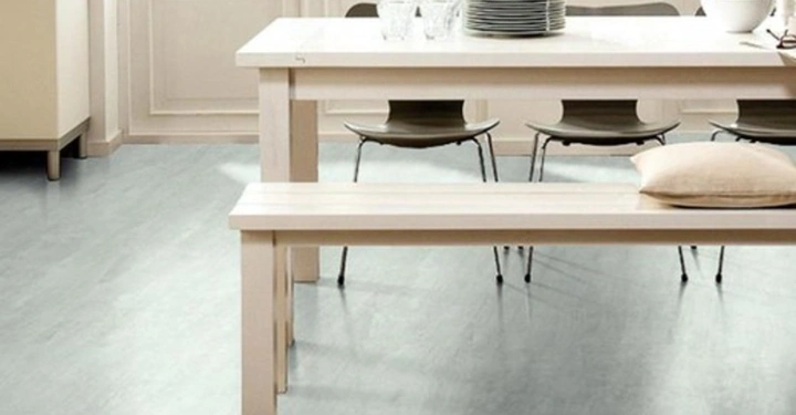 Ein Holztisch steht im Esszimmer neben einer Holzbank im modernen Design helle Wände und Fenster heller Bodenbelag im Hintergrund hängen Bilder und stehen Dekorationsgegenstände auf Möbeln.