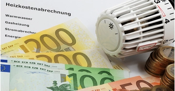 Eine Heizkostenabrechnung mit mehreren Hundert-Euro-Scheinen und Münzen, sowie einem Heizungsregler.