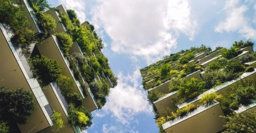 Hochhäuser mit üppigem Grün auf Balkonen ragen in den blauen Himmel mit weißen Wolken.