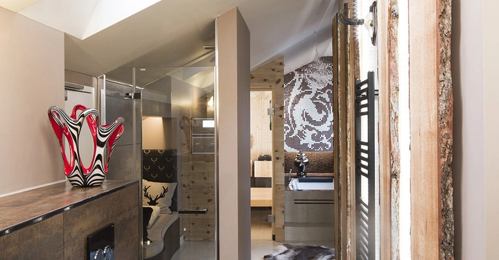 Eine moderne Toilette befindet sich unter einem Dachfenster mit natürlichem Licht. Im Hintergrund liegen eine Duschkabine und ein Waschbecken in einem stilvollen Badezimmer mit Holz- und Mosaikverzierungen.