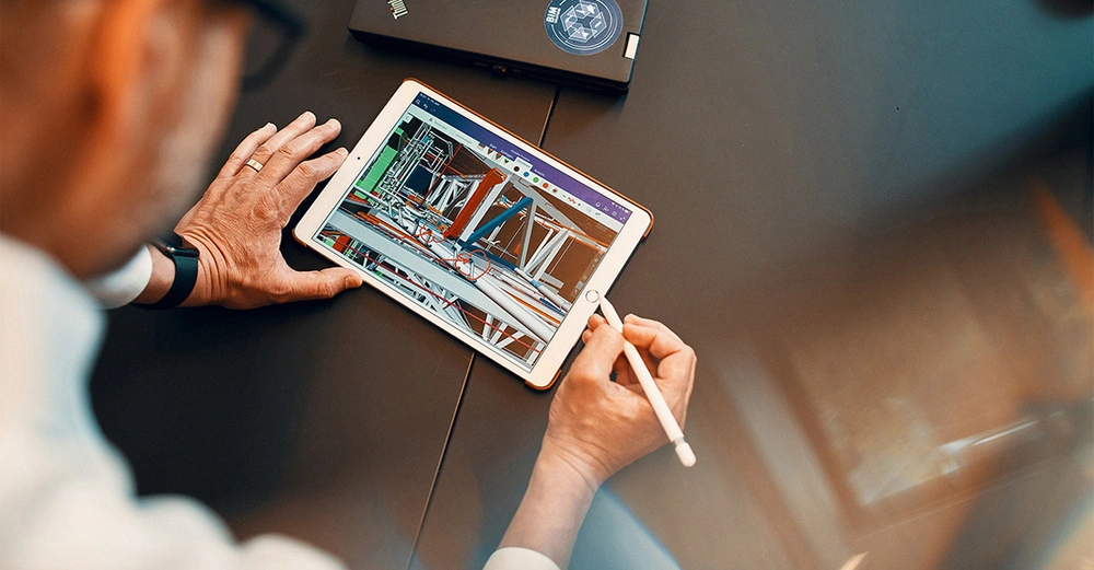 Tablet dargestellt Design während der Bearbeitung gepflegt auf einem dunklen Tisch mit einem Laptop im Hintergrund.