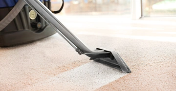 Saubsauger saugt über einen bräunlichen Teppich und hinterlässt einen sauberen weißen Streifen.