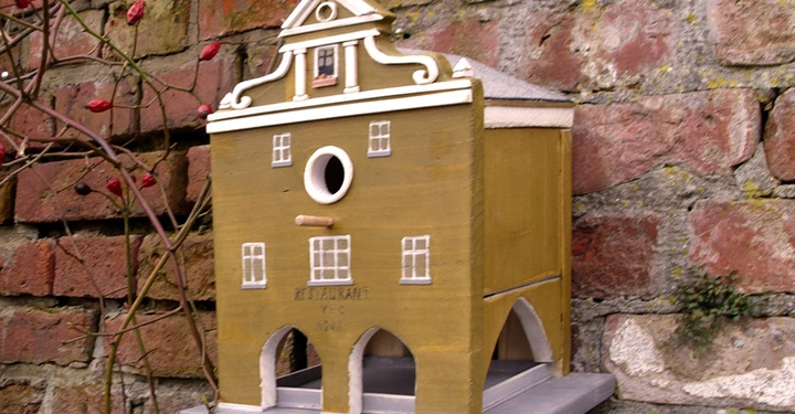 Galerie-Bild 7: Vogelhaus-Nachbildung eines Gebäudes an einer Ziegelsteinmauer befestigt einzelne Pflanzenranken umgeben Im Gebäude steht RESTAURANT Vög 1945
