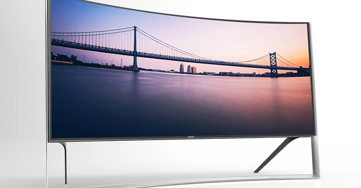 Galerie-Bild 4: Ein großer gekrümmter Fernseher zeigt ein Bild einer Brücke bei Sonnenuntergang Bildschirm auf weißem Hintergrund Text: Samsung