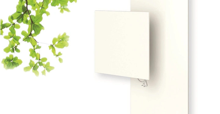 Quadratisches weißes Heizpaneel ist an einem rechteckigen weißen Paneel montiert; ein Kabel verbindet es mit einer Steckdose; grüne Blätter eines Baums hängen von der linken oberen Ecke herab