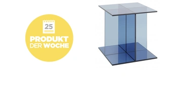 Ein blauer Glastisch stehend auf einer weißen Fläche links daneben ein gelber Kreis mit weißem Text 25 PRODUKT DER WOCHE.