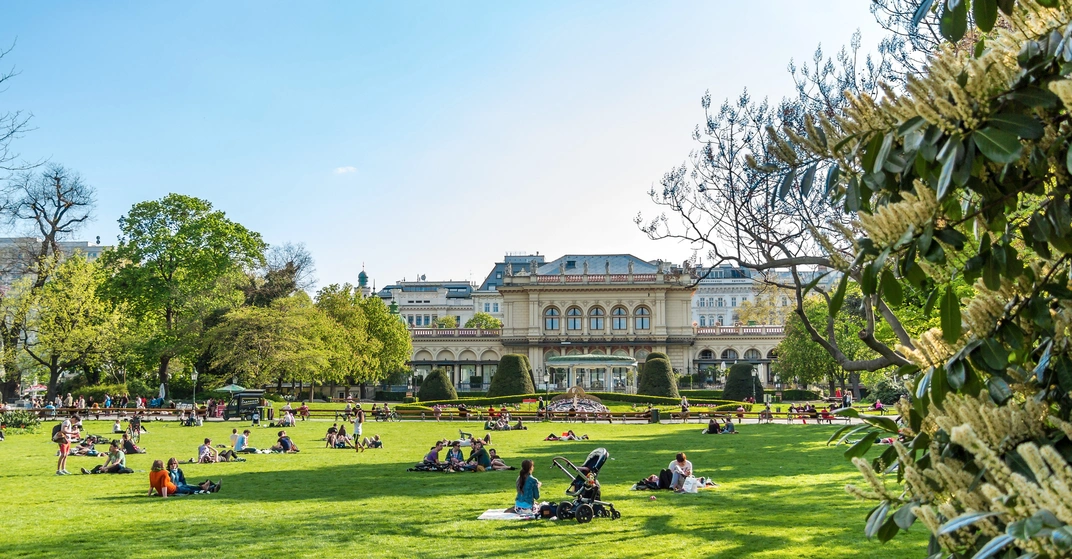 Ein grüner Wiener Park mit einer saftigen Wiese, auf der viele Leute picknicken - so könnte die klimafreundliche Stadt der Zukunft aussehen.