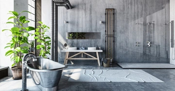 Freistehende Badewanne aus Metall neben Wachspflanzen links, zwei Waschbecken mit Spiegel auf Holzuntergestell in der Mitte, moderne Dusche mit Glaswand rechts in einem modernen, betonfarbenen Bad.