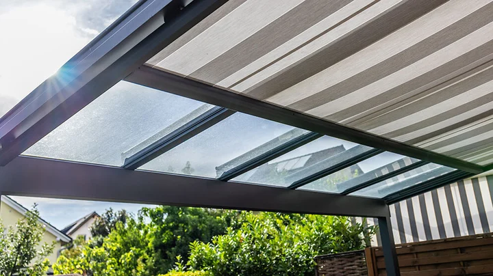 Außenliegender Sonnenschutz an einer Terrassenüberdachung mit Glasdach und Markise zum Schutz vor Sonne und Hitze.