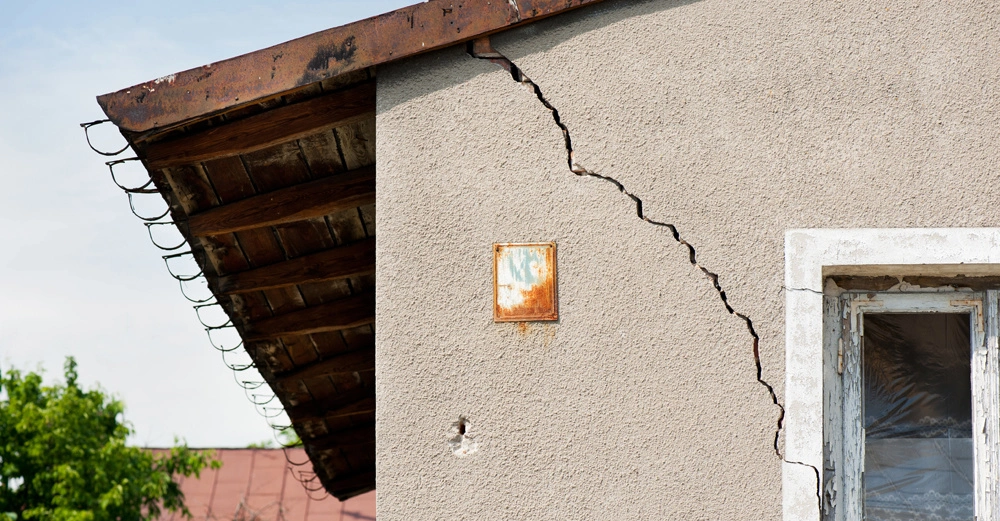 sehr altes, kleines Haus mit tiefem Riss in der Außenfassade, der vom Dach bis zum Fenster reicht
