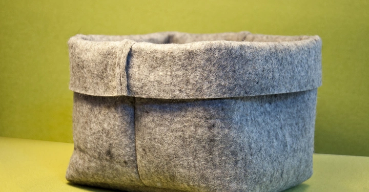 Galerie-Bild 6: Grauer Filzkorb steht auf einer gelbgrünen Oberfläche vor einer gleichfarbigen Wand.