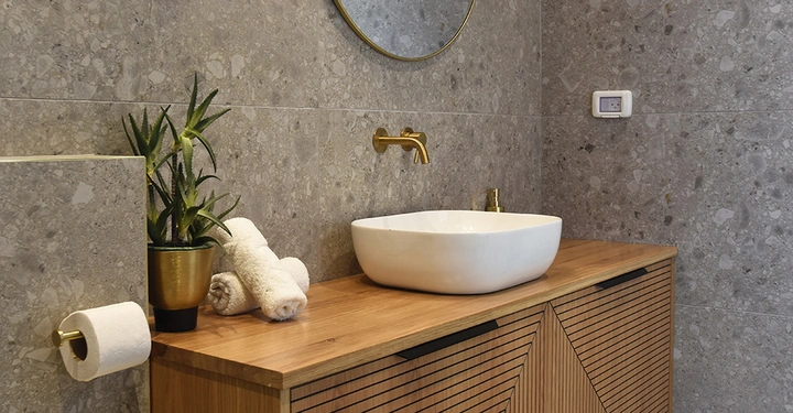 Galerie-Bild 3: Modernes Badezimmer mit Naturstein, Holz und Goldakzenten.