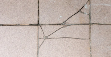 Terrassenboden mit gesprungenen Keramikfliesen und kaputten Fugen